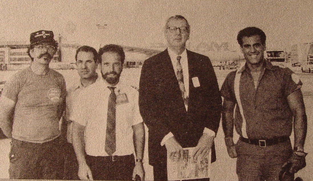 1980s  Pan Am Chairman C. Edward Acker (tall with glasses) visits with ground staff members Angelo Klunich (left with mustache) John Jamatta (with beard & tie) and Al Hernandez with single stripe shirt on the left of Ed Acker at the Pan Am Shuttle at LaGuardia Airport in New York.